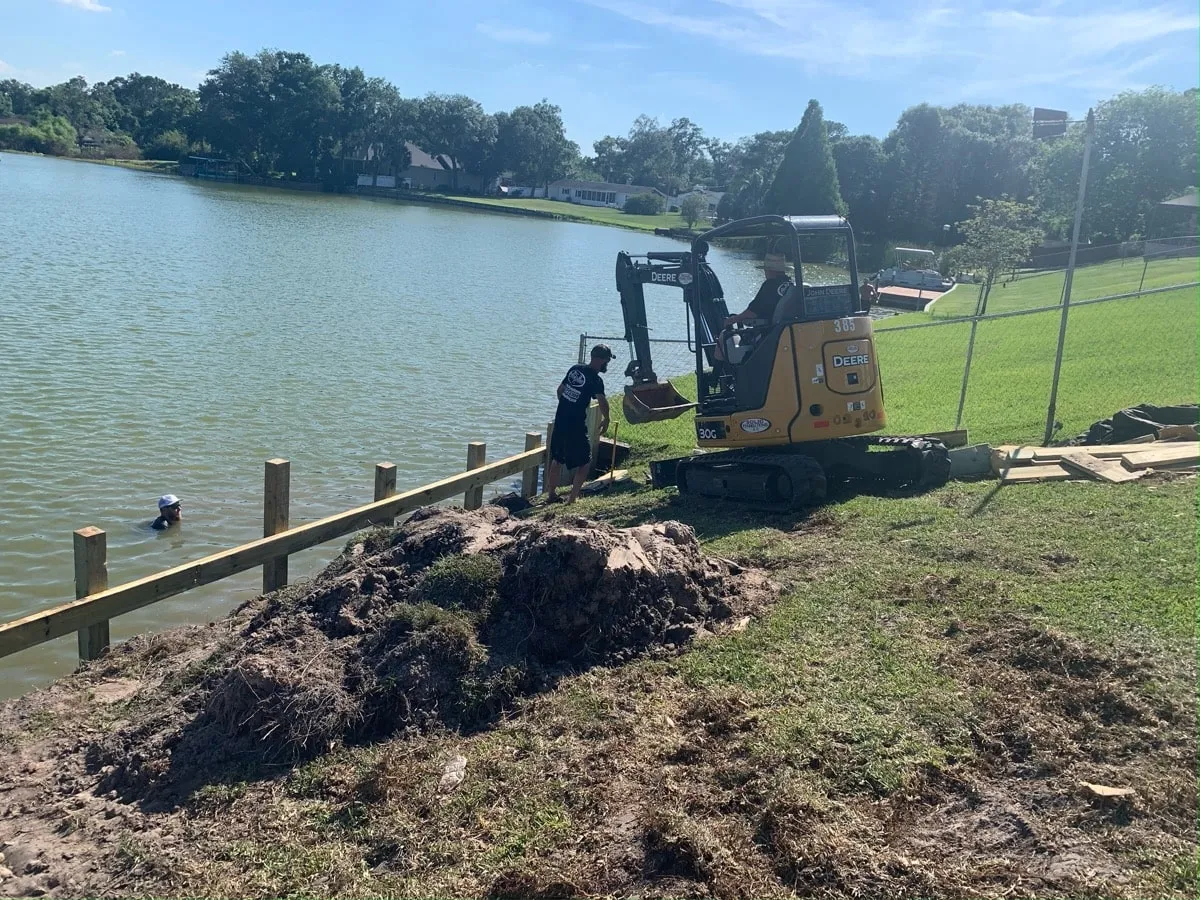 Excavator installing posts for a new bulkhead on a lakefront lot