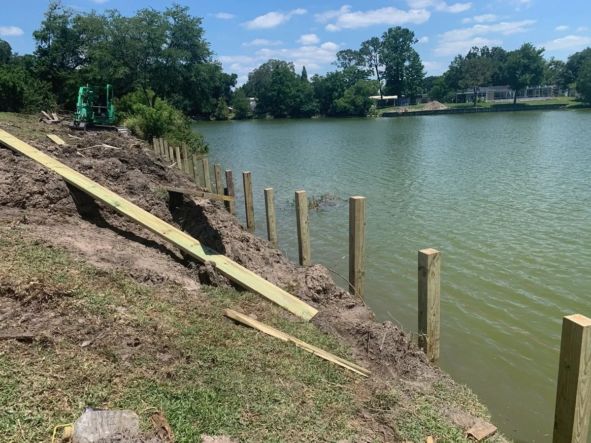Row of new pilings and bulkhead boards along a lake